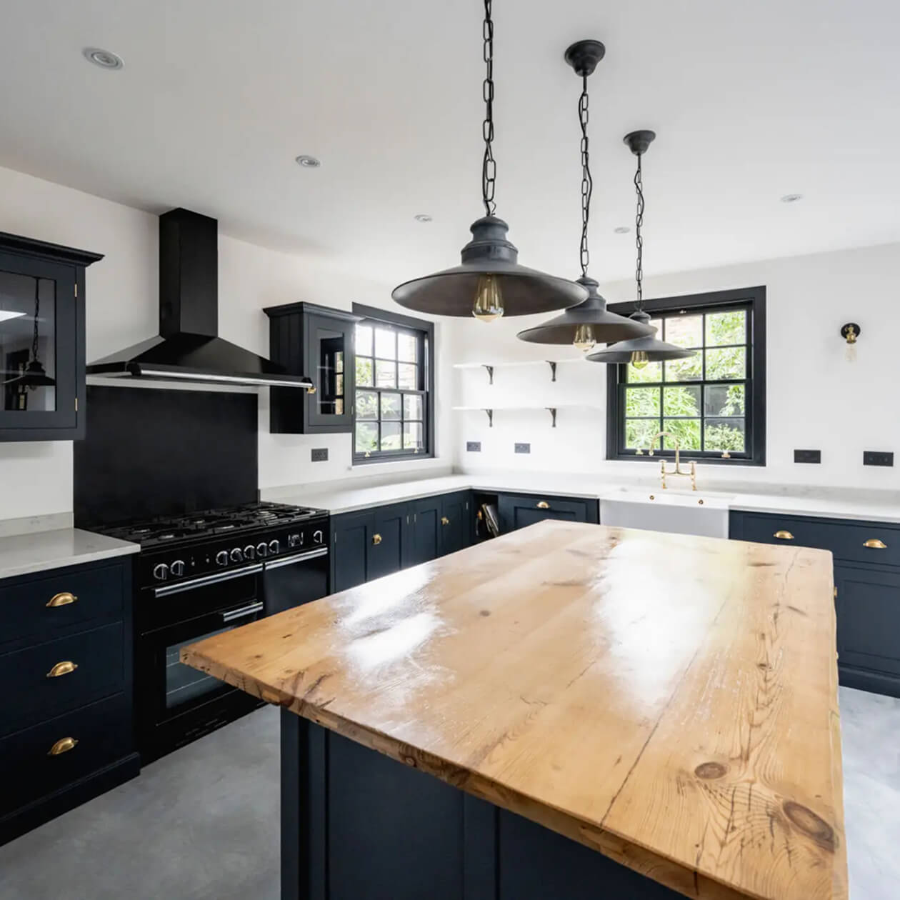 Modern kitchen with wooden island and pendant lights.